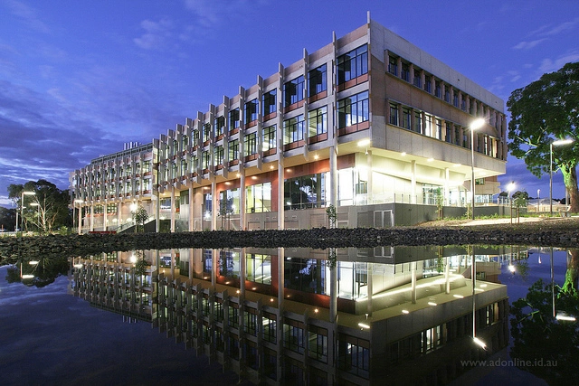 The AgriBio building illuminated at night, reflected in a pond
